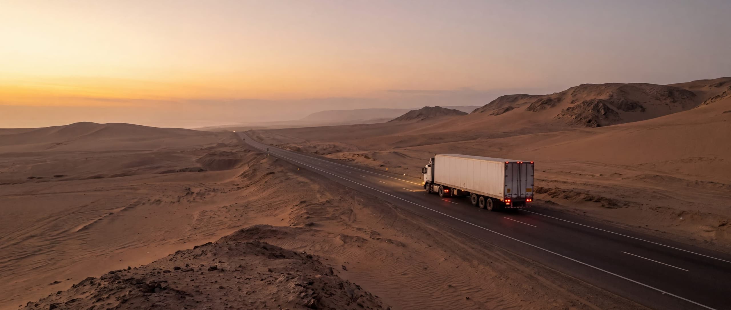 Camión de carga en la carretera Panamericana Norte al atardecer, en el desierto costero del Perú